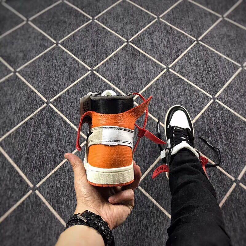 Rear view showing the orange heel panels, black collar, and light-colored heel overlay.
