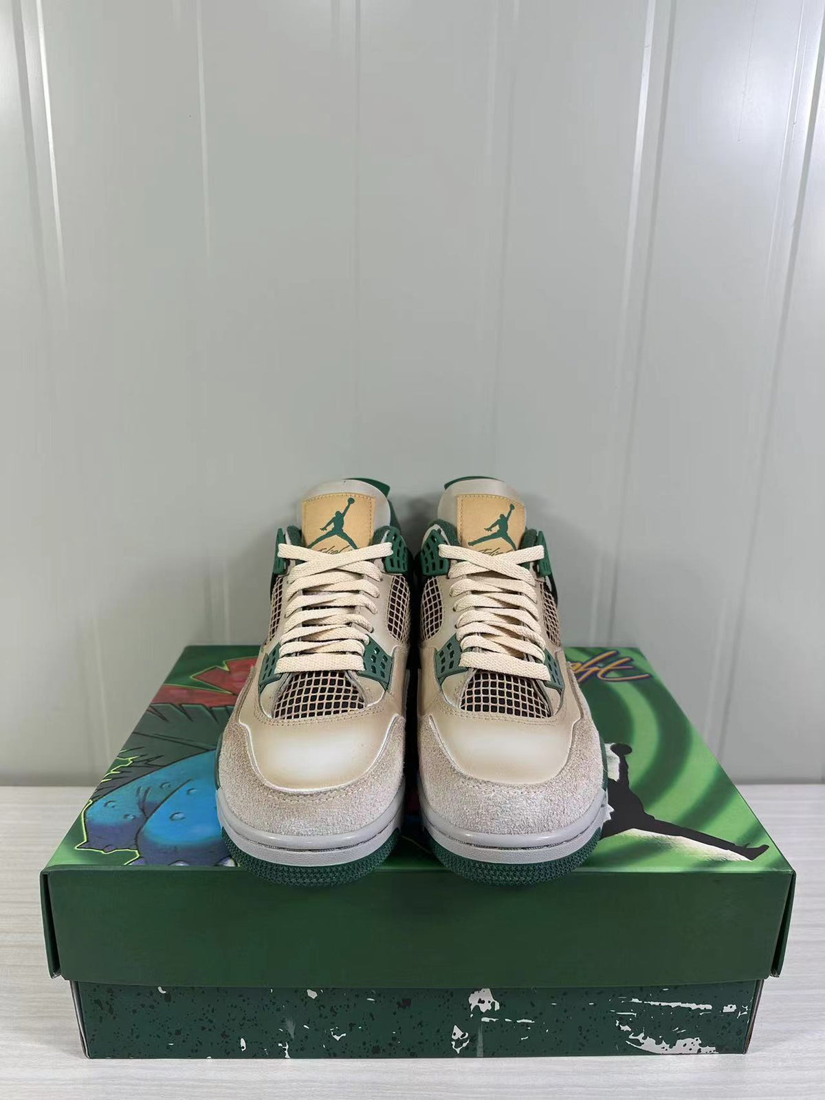 Front view of the pair showing cream laces, green lace supports, mesh panels and tan tongue labels.