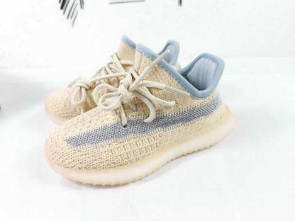 Pair of linen-yellow sneakers with gray side stripes, matching laces, and translucent soles.