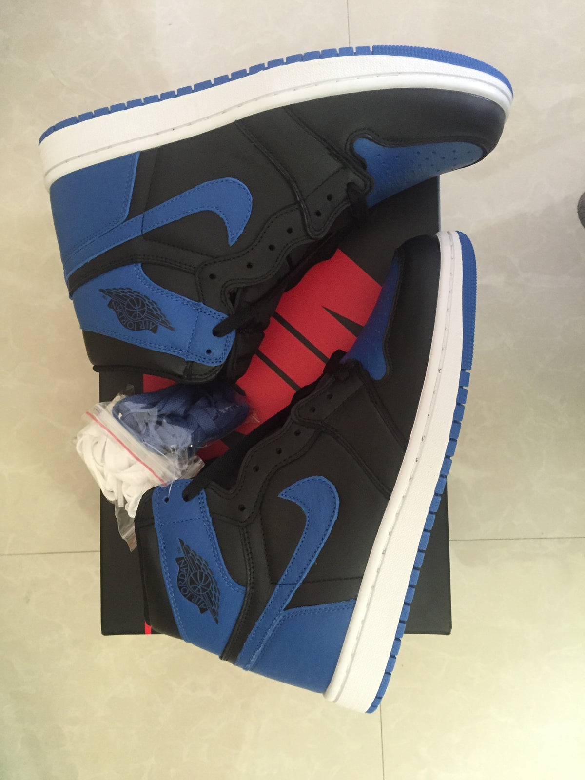 Top and side view of black and royal blue high-top sneakers with white midsoles and blue outsoles.
