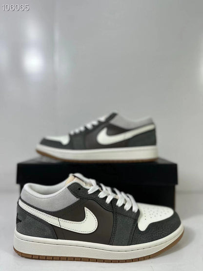 Pair of black, white and grey low-top sneakers shown from a side angle on a black shoe box.