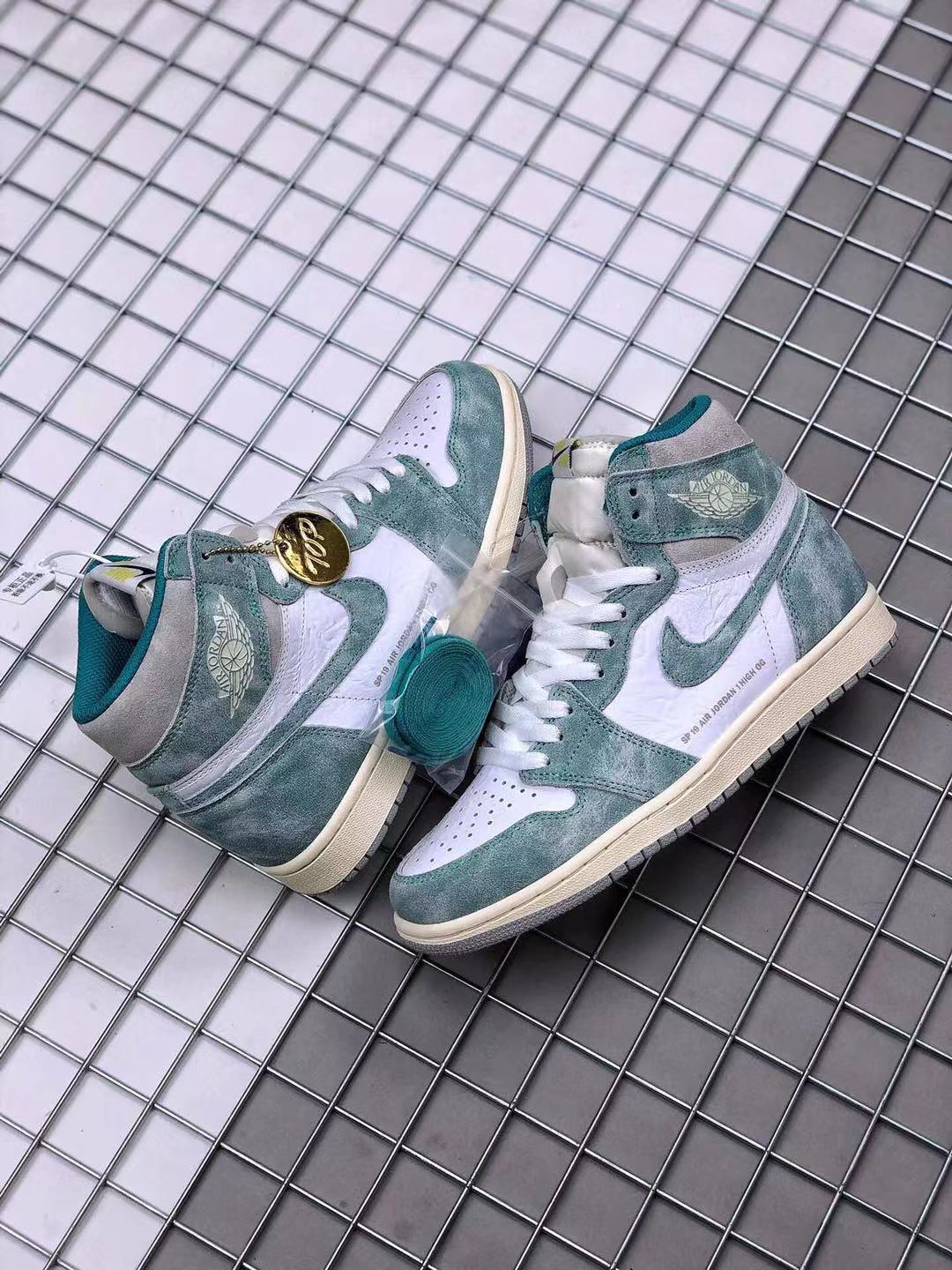 Pair of teal-green and white high-top sneakers displayed together with spare laces and a decorative hangtag.