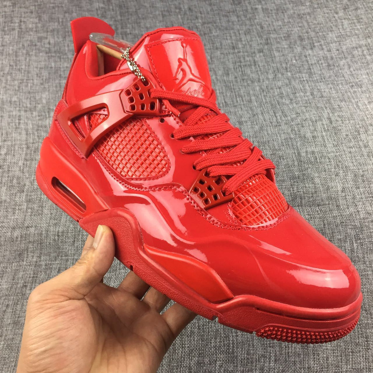 Close-up three-quarter view of the glossy red toe box, laces, tongue, side panel, and midsole.