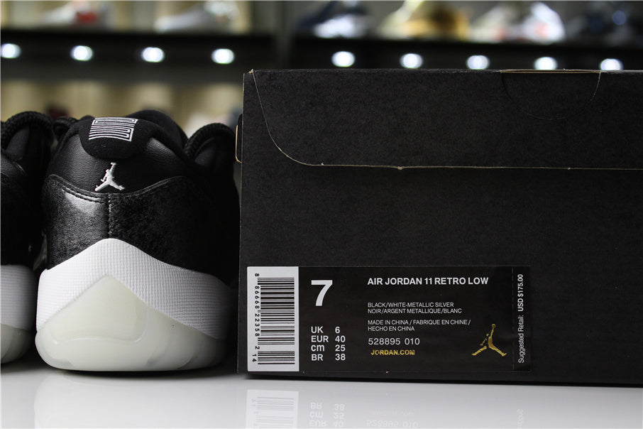 Rear view of black and silver low-top sneakers beside a box labeled Air Jordan 11 Retro Low, with size 7, EU 40, and code 528895 010 visible.