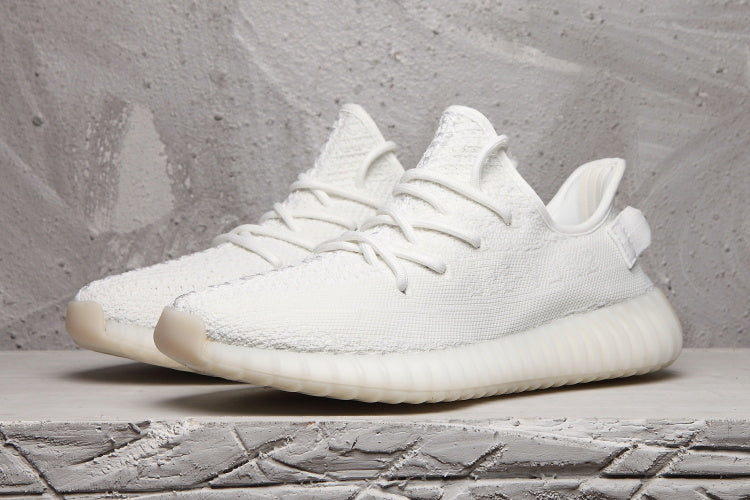 White Yeezy 350 V2 sneakers shown together from a front three-quarter angle.