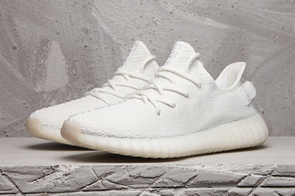 White Yeezy 350 V2 sneakers shown together from a front three-quarter angle.