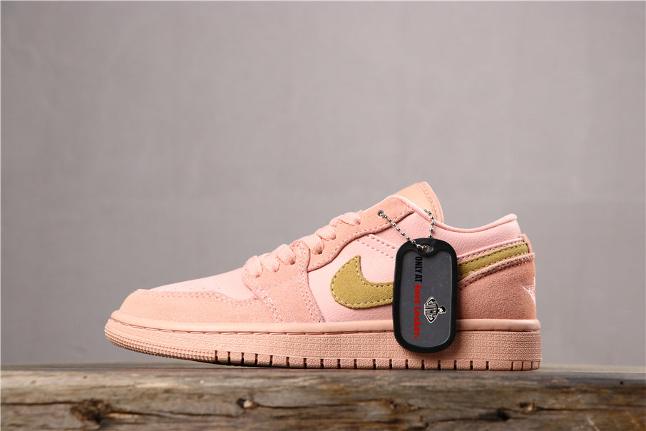 Angled side view of the coral pink sneaker showing its lace-up closure, gold-toned side emblem, padded collar, and attached hangtag.