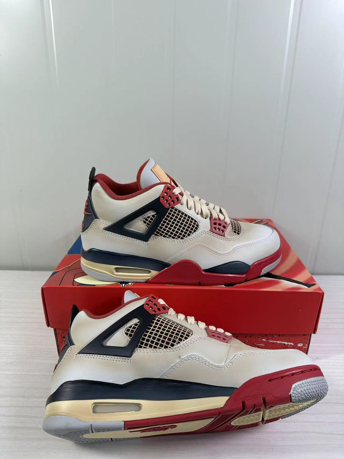 Detailed angled view of the Jordan Air Jordan 4 Retro pair, highlighting the mesh panels, lace supports, and outsole.