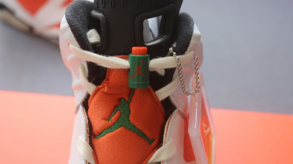 Close-up of the orange tongue, green Jumpman emblem, white laces, and green-and-orange lace toggle.