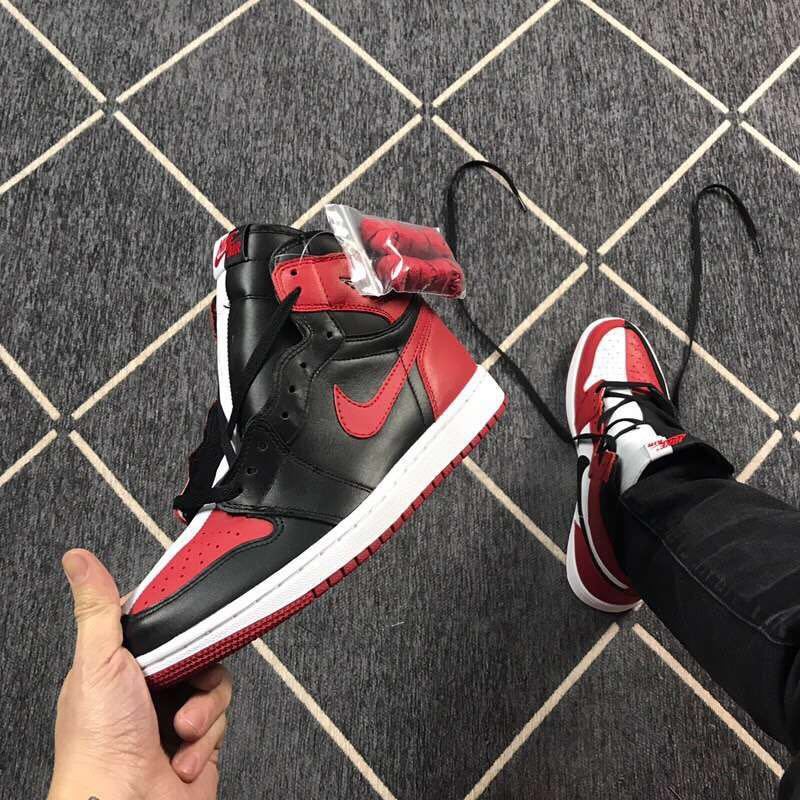 Angled view of a black and red high-top sneaker with a clear accessory package near the collar.