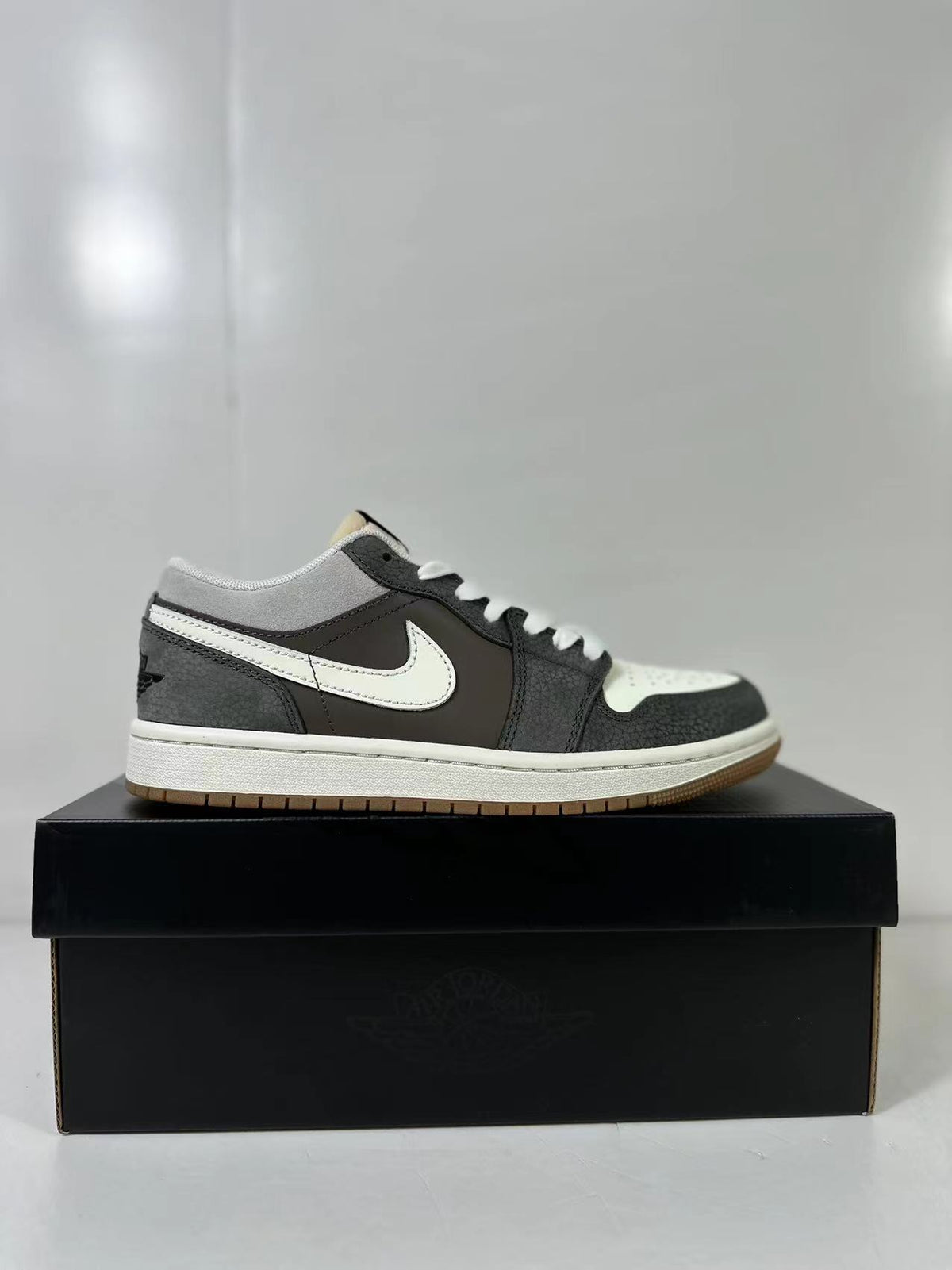 Single low-top sneaker shown in side profile with grey collar panels, black overlays and a white Swoosh.