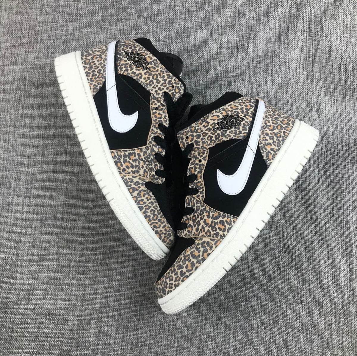 Top-down view of the pair showing leopard-print overlays, black panels, white Swooshes, and white outsoles.