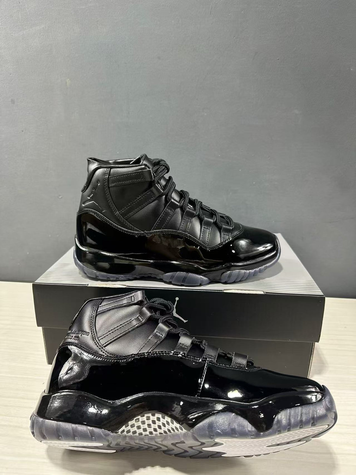 Side and outsole view of two black high-top sneakers showing glossy panels and translucent gray traction sections.
