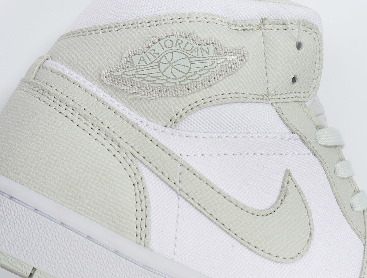 Close-up of the light Spruce Jordan Wings logo, Swoosh, stitching, and textured overlays.