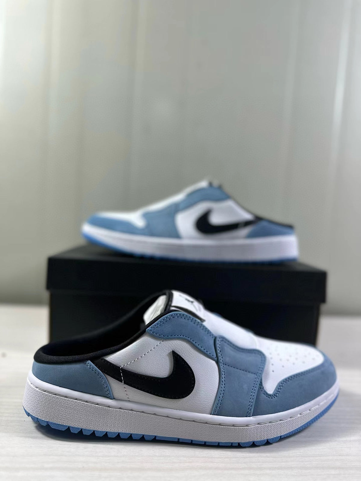 Blue, white, and black Jordan mule sneaker shown from the side with the shoe box behind it.