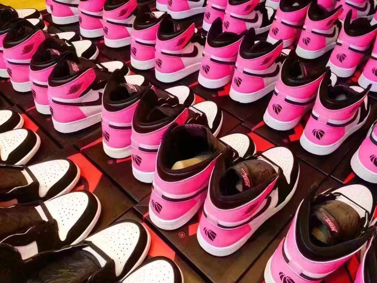Multiple pairs of the pink, black, and white high-top sneakers displayed together.