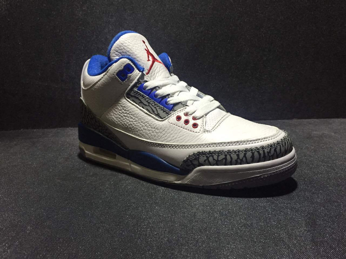 Front three-quarter view of the white and blue high-top sneaker with red tongue branding and elephant-print toe overlay.