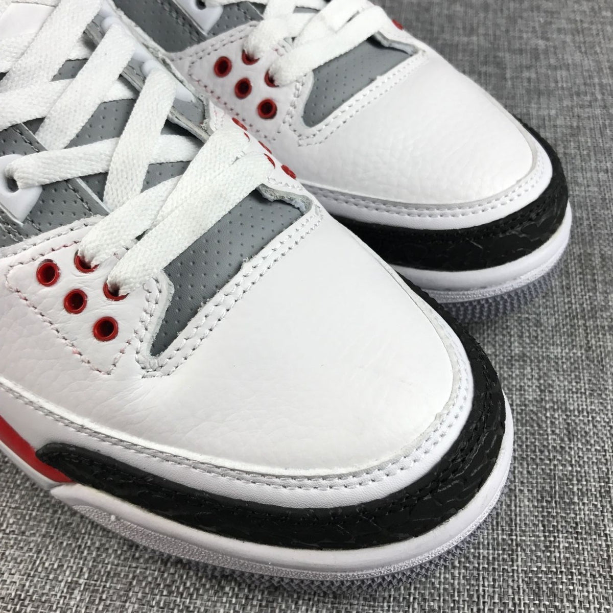 Close-up of the perforated gray lace panel, white toe box, and black textured toe overlay.