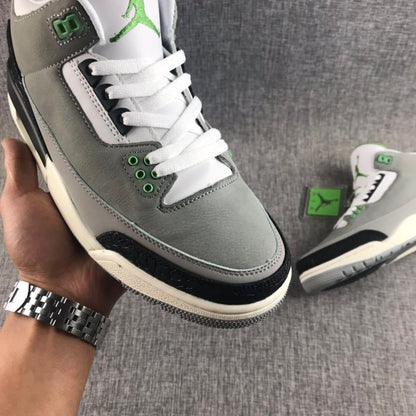 Close-up side view showing the gray upper, white laces, green eyelets, and black textured toe overlay.