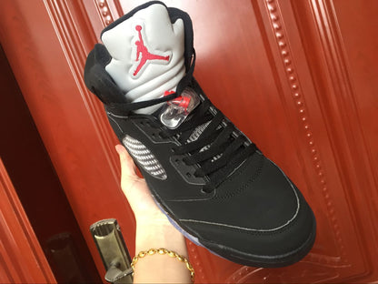 Single black high-top sneaker held at an angle, showing the lacing area, silver side panel, and white tongue.