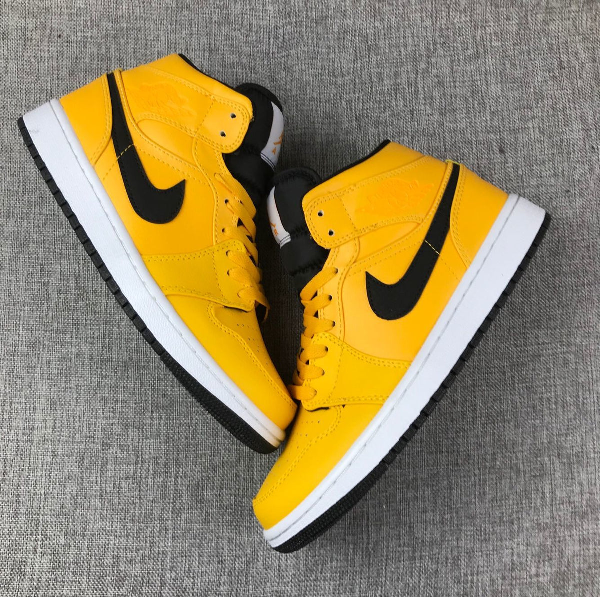 Top-down view of the pair of yellow mid-top sneakers with black accents.