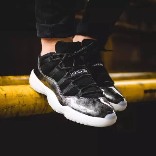 Lifestyle image of the black and silver low-top sneakers being worn with dark clothing.