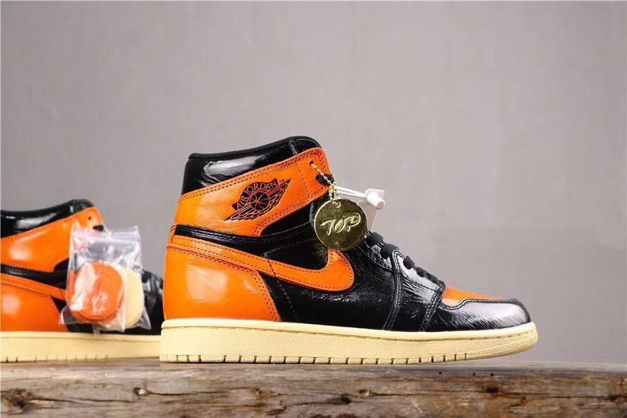 Side profile of a black and orange high-top sneaker with a cream-colored outsole and an attached round hangtag.