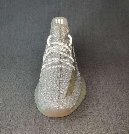Front three-quarter view showing the woven toe box, tonal laces, olive side stripe, and ribbed sole.