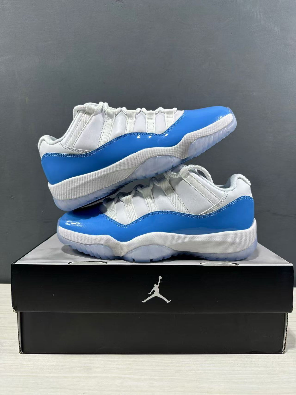Pair of white and blue low-top sneakers arranged on a black Jordan shoe box.