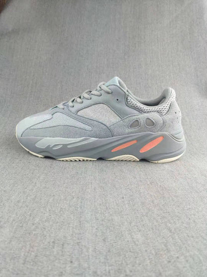 Side profile of a gray sneaker with layered panels, mesh detailing, coral sole inserts, and a textured outsole.