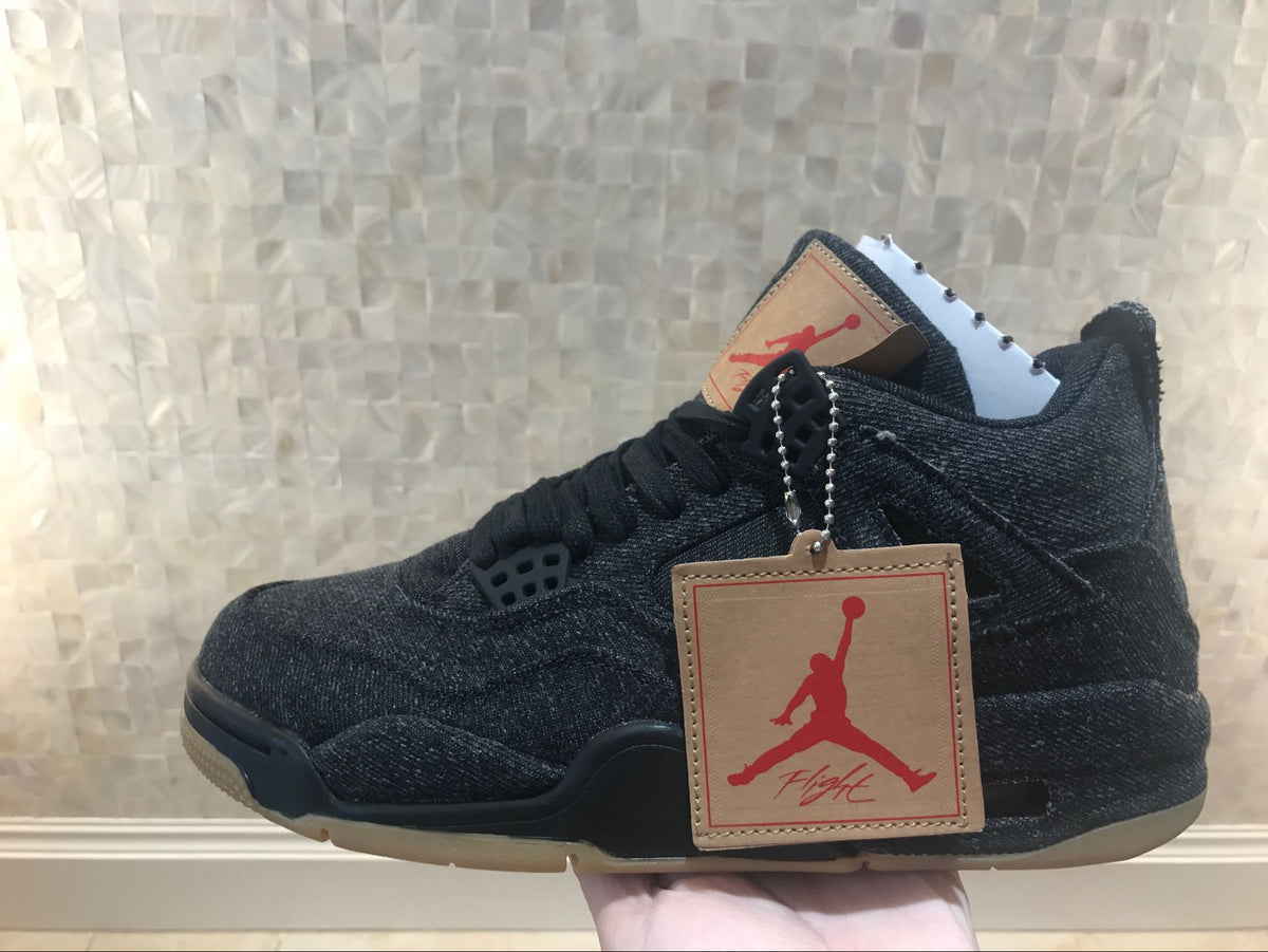Side view with a tan-and-red Jordan hangtag attached to the black sneaker.