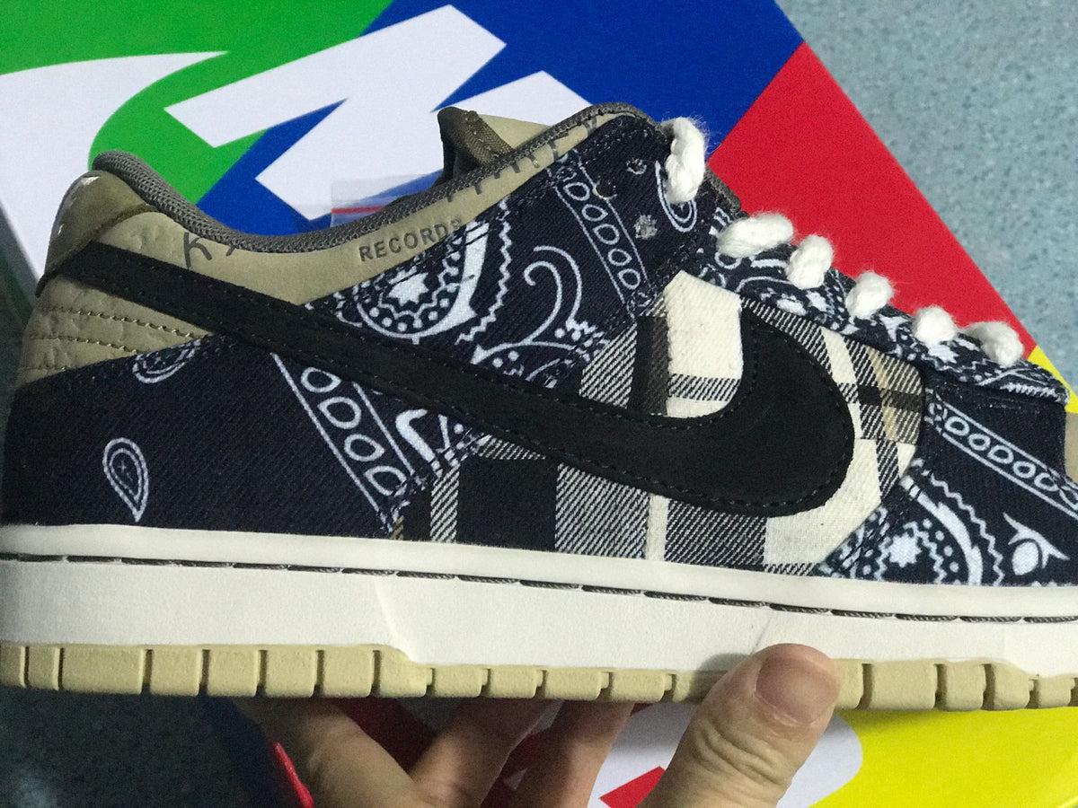 Close side view showing black patterned fabric, contrasting plaid panels, the dark Swoosh, and the textured outsole.