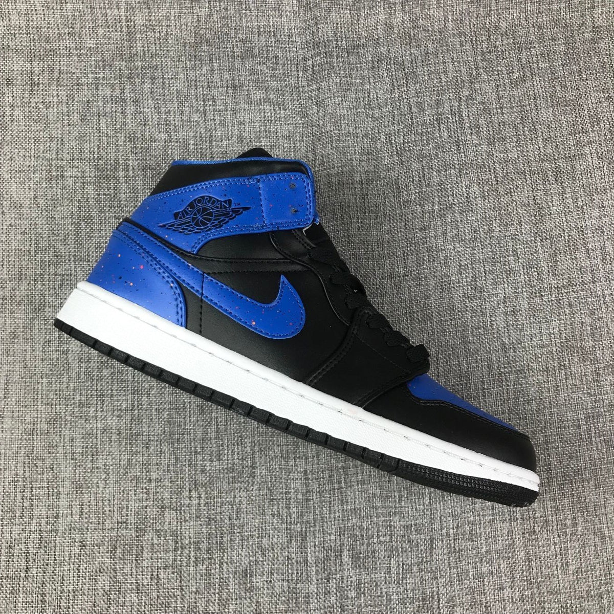 Single black and blue high-top sneaker shown in a diagonal side view.