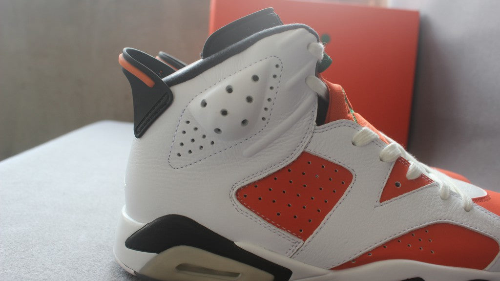 Close-up of the lateral upper showing the perforated orange side panel, white overlays, and black heel accent.