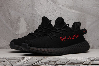 Side-by-side view of black lace-up sneakers with red side lettering.