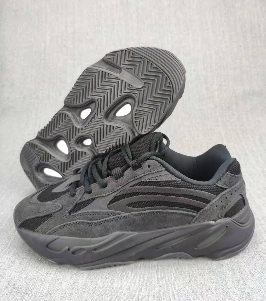 Charcoal and gray 700 V2 sneaker shown from the side with the outsole visible behind it.