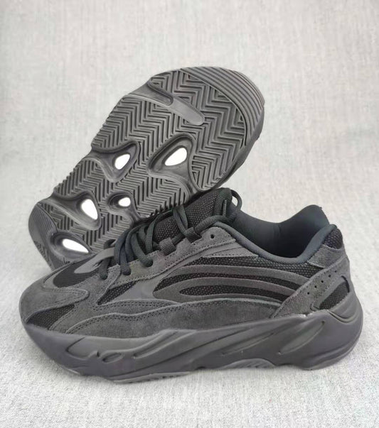 Charcoal and gray 700 V2 sneaker shown from the side with the outsole visible behind it.