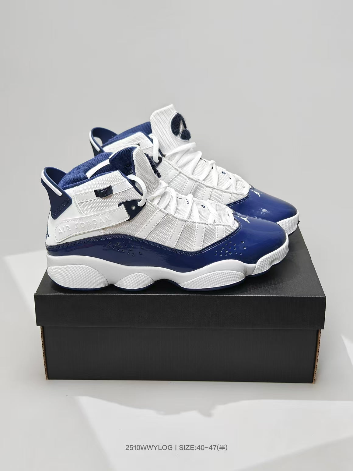 Pair of white and navy Jordan 6 Rings sneakers displayed on a black shoebox.