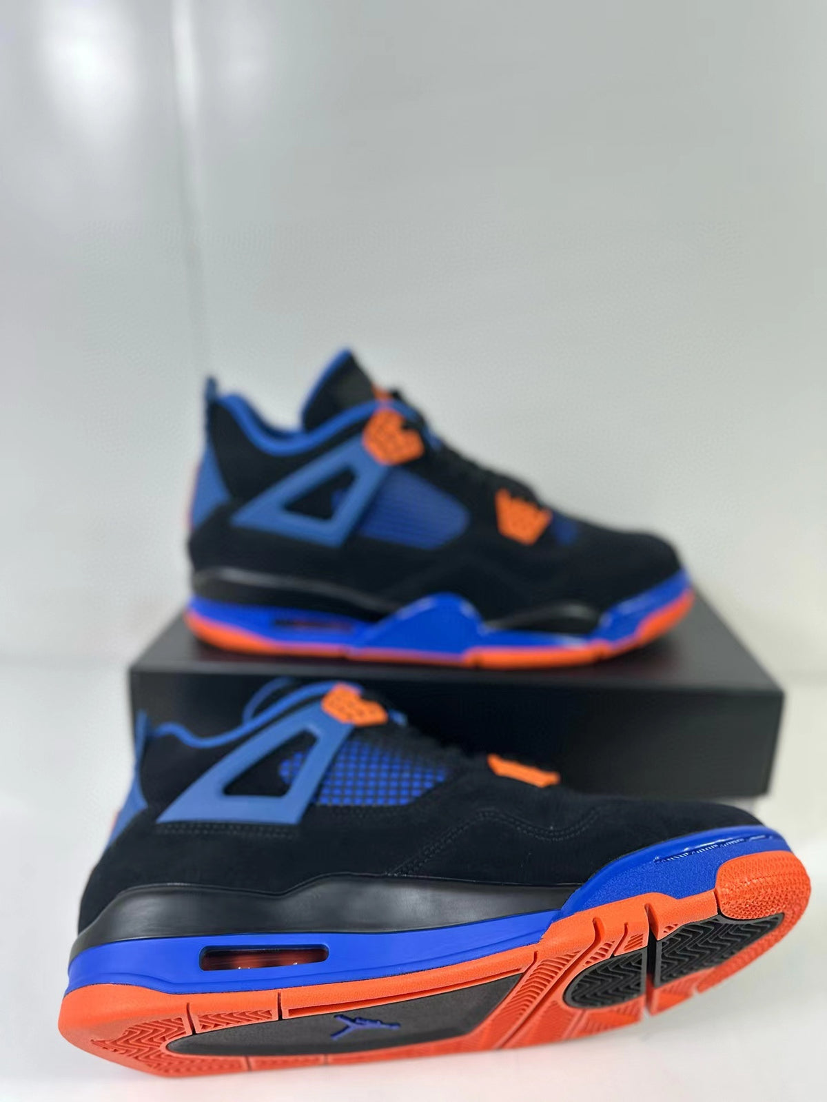 Angled view highlighting the Air Jordan 4 side profile, visible air unit and orange-blue outsole.