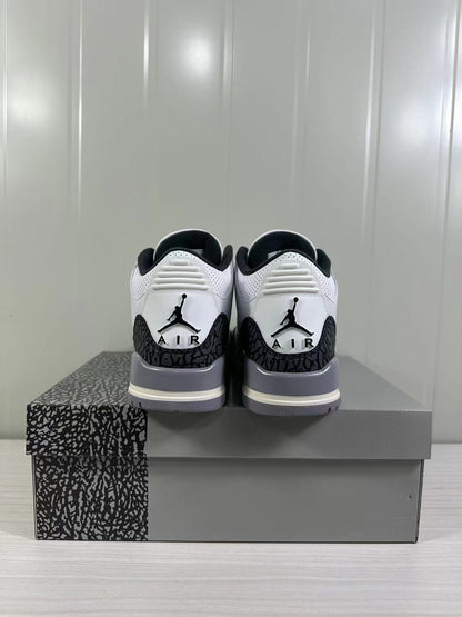 Rear view of white and grey Air Jordan 3 sneakers displayed on a patterned shoebox.