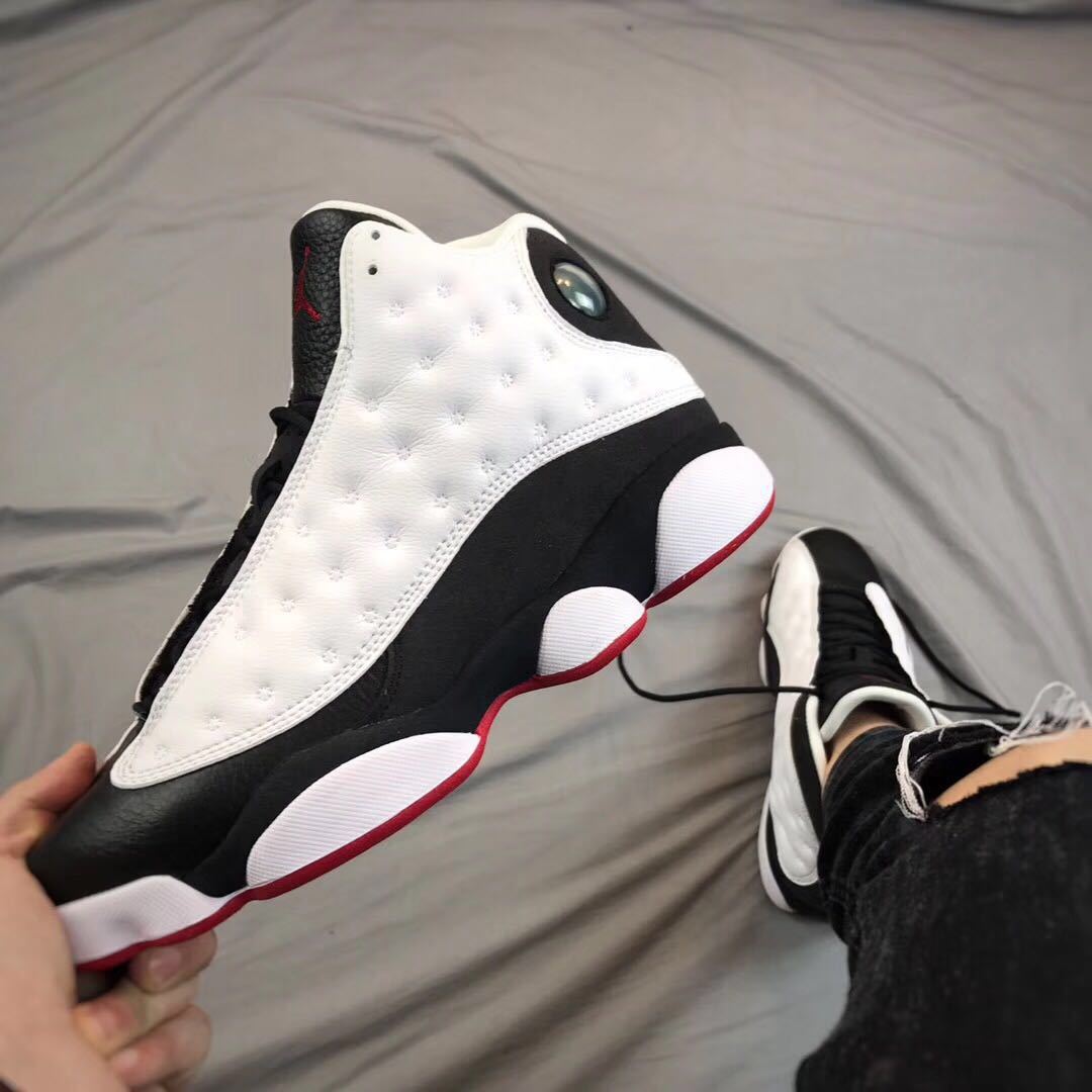 Close side view highlighting the white textured upper, black lower panel, circular side detail, and red outsole.