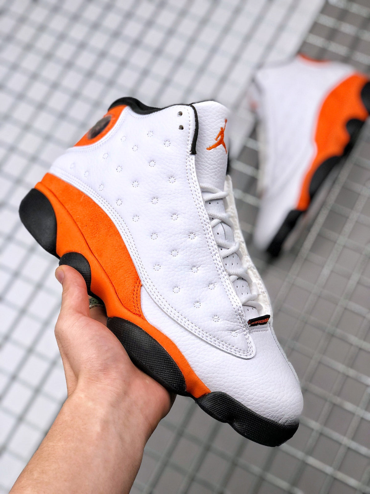 Angled side view of the white and orange Air Jordan 13 sneakers