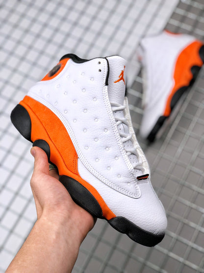 Angled side view of the white and orange Air Jordan 13 sneakers