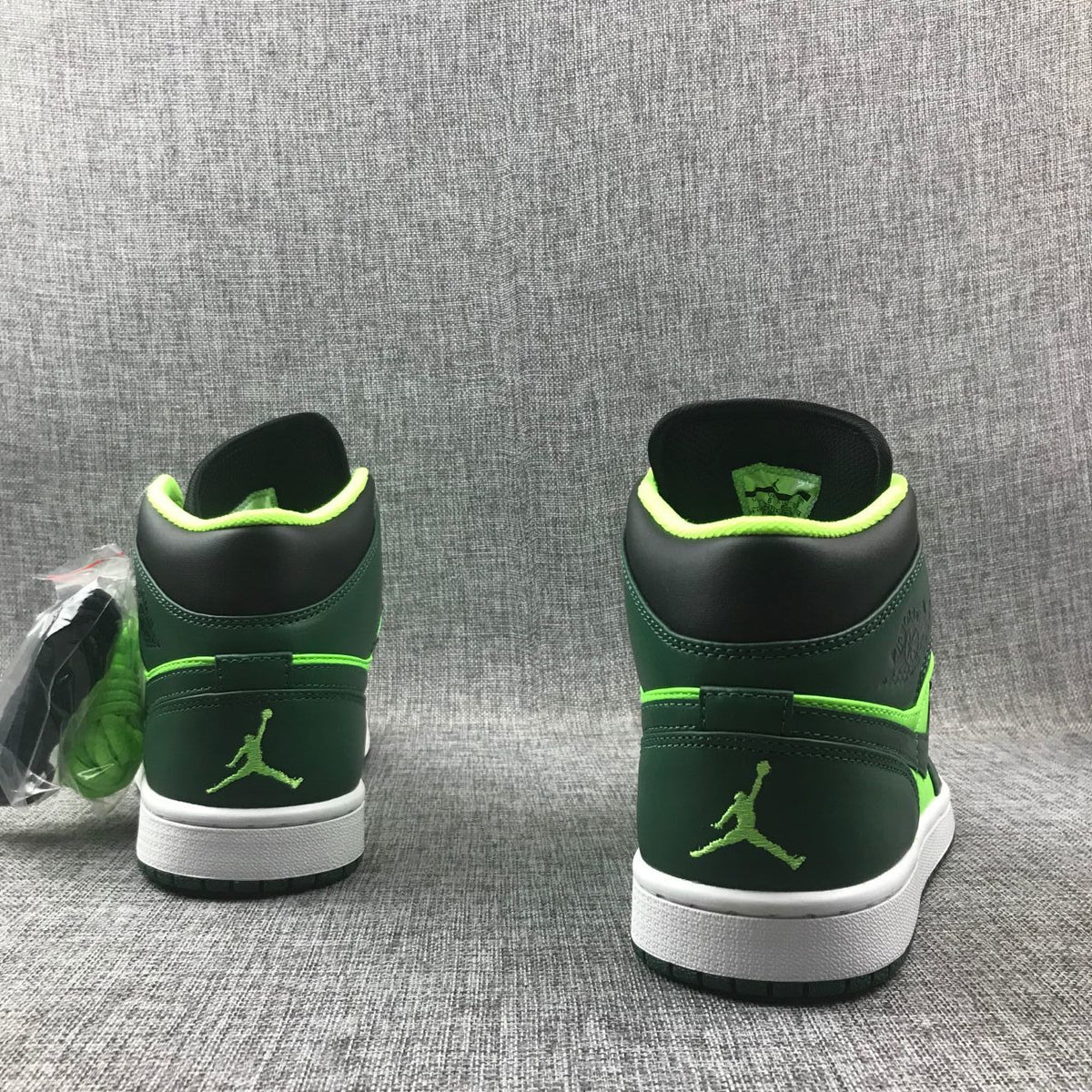 Rear view of the pair showing fluorescent green Jordan heel logos and white midsoles.