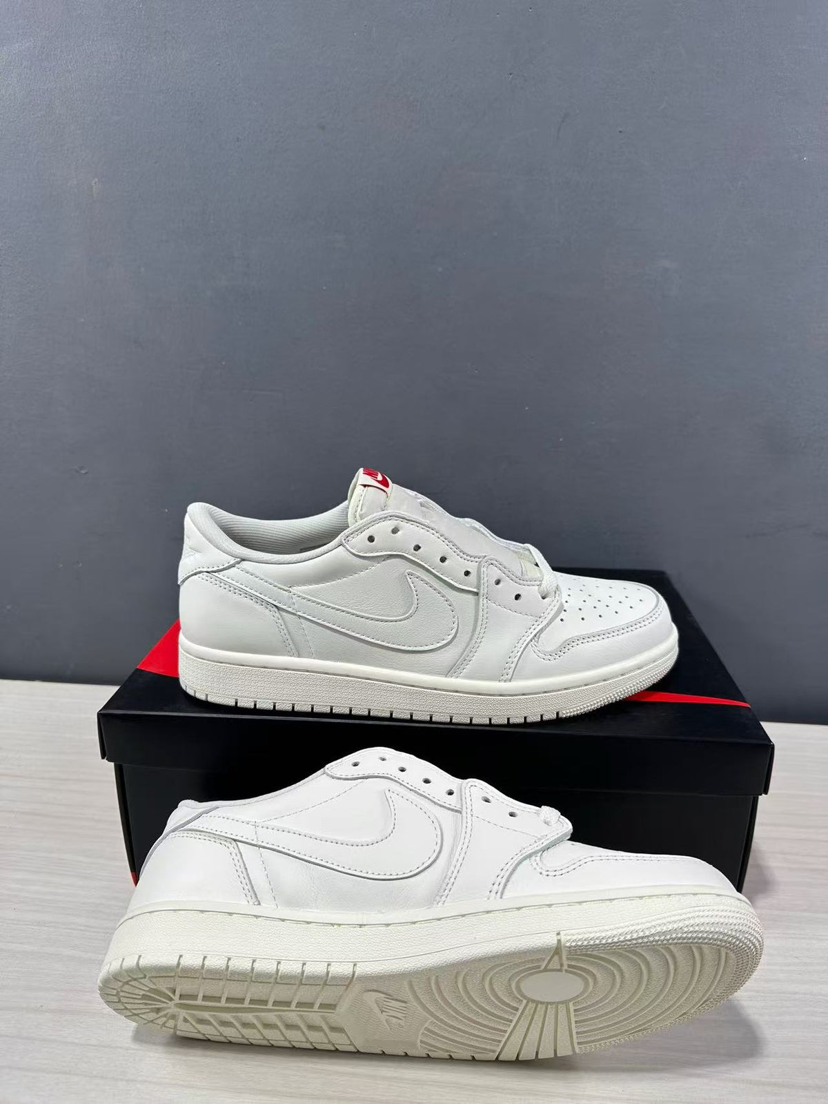 White low-top Jordan sneakers shown from the side and underside, highlighting the layered upper and circular outsole tread.