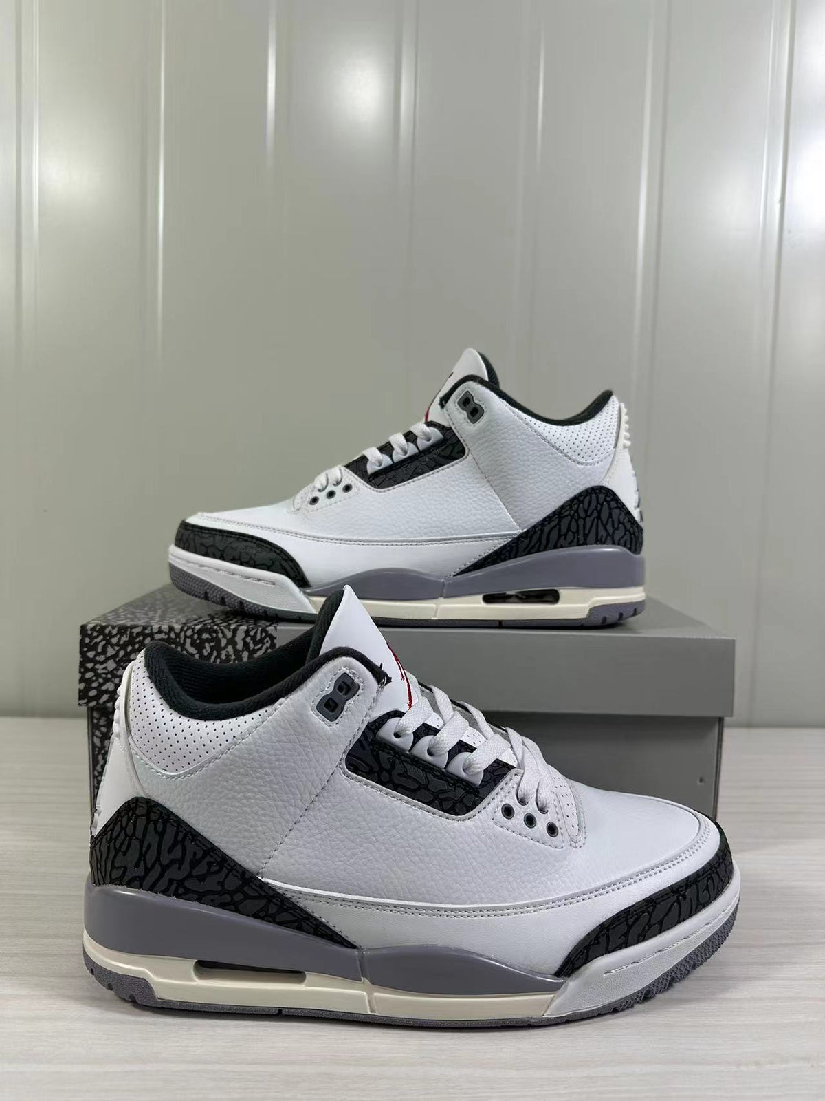Angled product view of the white and grey Air Jordan 3 sneakers with one shoe in the foreground.