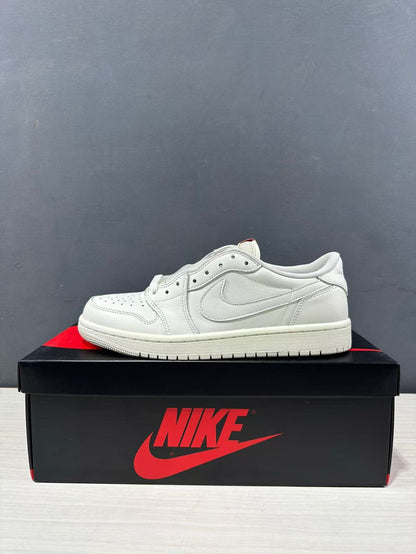 Side profile of a white low-top Jordan sneaker on a shoe box, showing the perforated toe, layered panels, and padded collar.