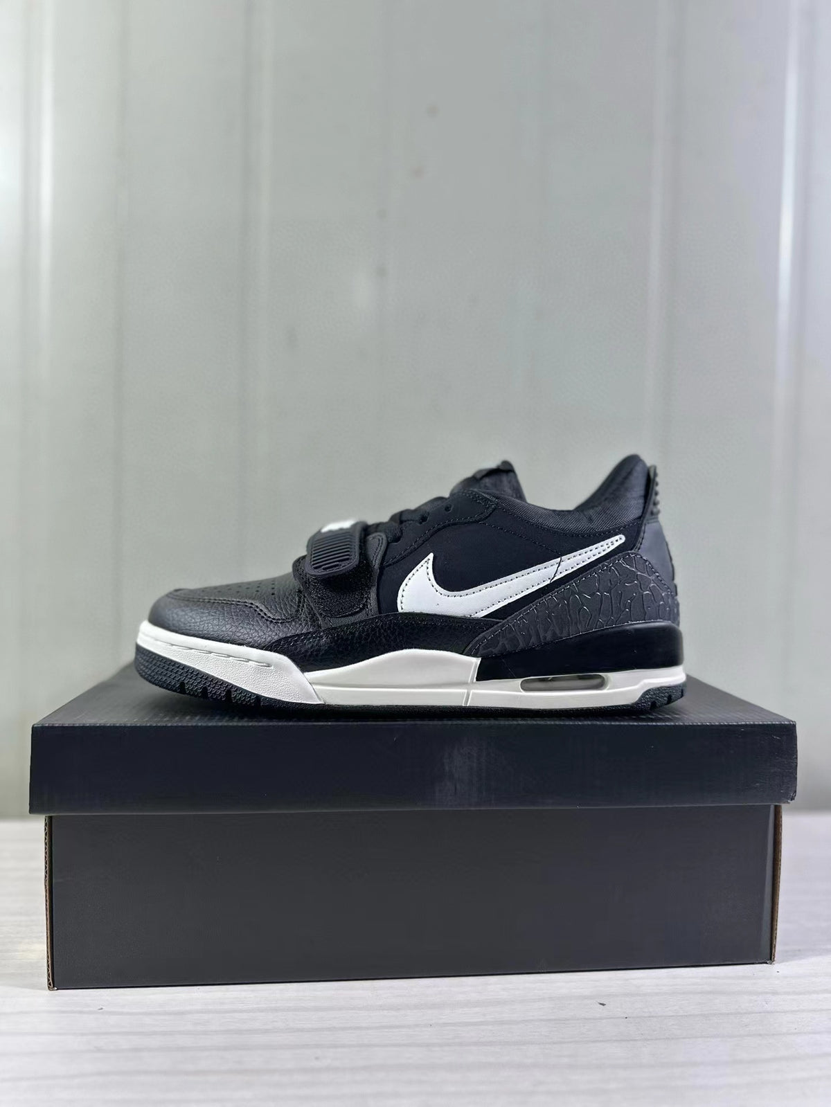 Side profile of a black and white Jordan Legacy 312 sneaker displayed on a black shoebox.