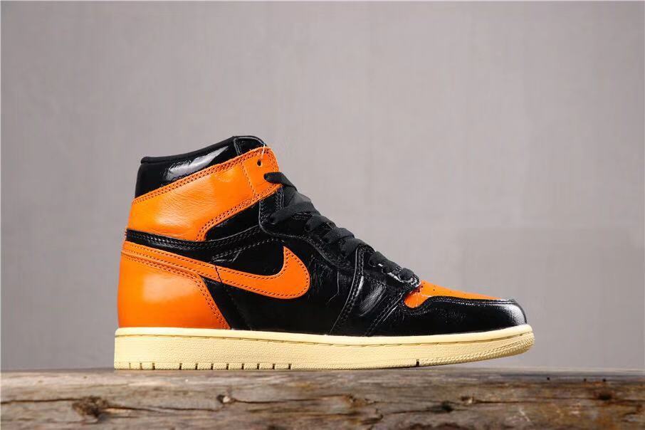 Side profile of a single black and orange high-top sneaker with an orange Swoosh and cream-colored outsole.