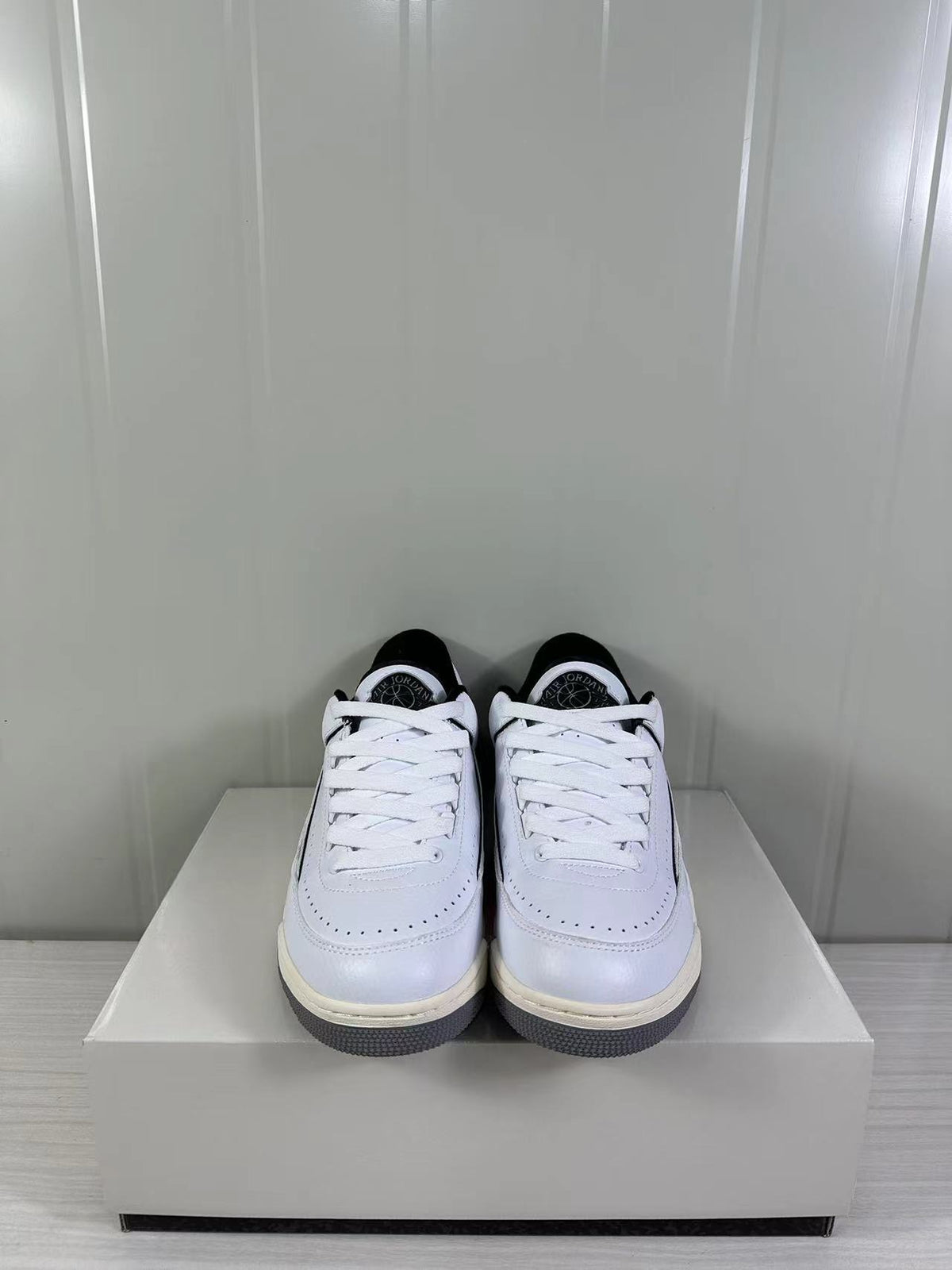 Front view of the white and black low-top sneakers with white laces and perforated toe panels.